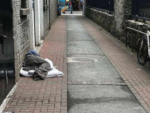 A homeless man sleeping on Church Lane in the city.