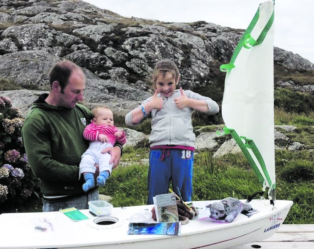Eight year-old Méabh Ní Ghionnáin poses with her father, Stiofán Ó Gionnáin, and younger brother. The family found the Lancer, an unmanned sailboat student Kaitlyn Dow built this spring for her marine science class at Waterford High School in Connecticut, US. The boat held stuffed animals, a t-shirt and messages from the American students.