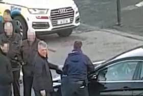 An armed plainclothes detective hold a machete with a two-foot blade, while another detains a man at the funeral.