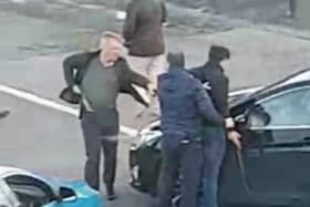 Armed detectives detain a man outside Mervue church yesterday afternoon.