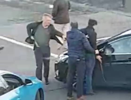 Armed detectives detain a man outside Mervue church yesterday afternoon.