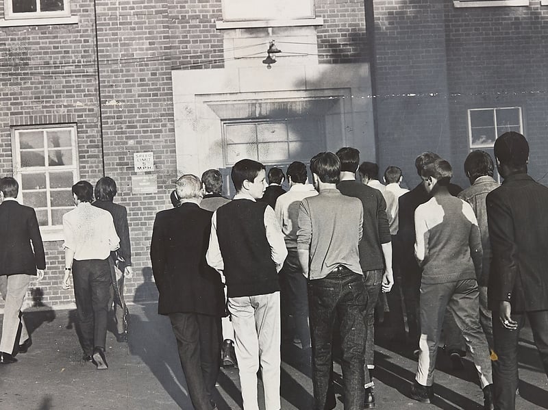 A crowd of young supporters moves toward the entrance of a building in Smethwick on June 3, 1970, ahead of a high-profile general election campaign rally held by Enoch Powell. Photographed from behind, the group local youths headed inside to hear Powell kick off his electioneering trail in the town. The moment captures the intense political atmosphere, youth subcultures, and sharp local debate that defined the run-up to the June 1970 general election across the West Midlands. Do you remember the tense political atmosphere and campaign rallies around the region during the 1970 general election? What are your memories of youth culture and political gatherings in the town back then?