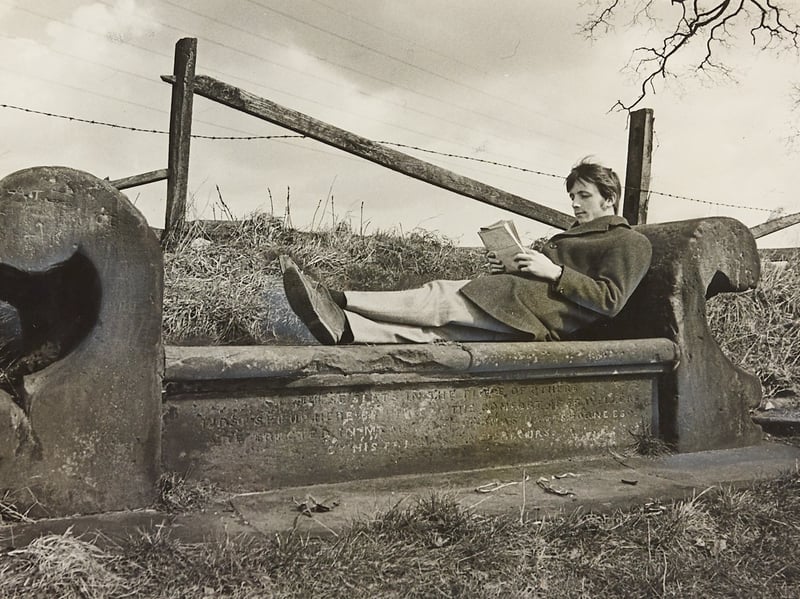 A weary traveller reclines comfortably with a good book on a carved stone settee along Tixall Road near Stafford in April 1970. Inscribed with the welcoming words "For the weary traveller," the historic stone bench offered a tranquil spot to pause and soak in the spring sunshine alongside the rural Staffordshire countryside. The idyllic scene captures a slower pace of life, showcasing the charming roadside landmarks that have long welcomed wanderers across the region. Do you remember passing or stopping by this carved stone settee along Tixall Road? What are your favourite quiet spots or quirky roadside landmarks around Staffordshire?