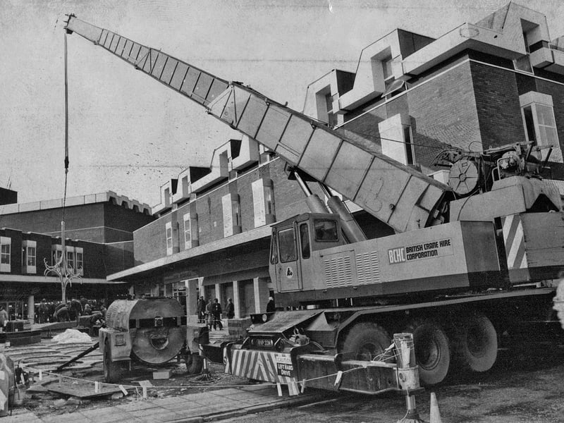 Traffic in Stourbridge High Street had to weave around a giant mobile crane in November 1975 as work took place to lower the ornamental fountain into position at the new Ryemarket shopping precinct. It must have been quite a sight for shoppers and passing motorists as the huge piece was carefully manoeuvred into place. Do you remember the Ryemarket when it was new, or the fountain that became one of its familiar features?