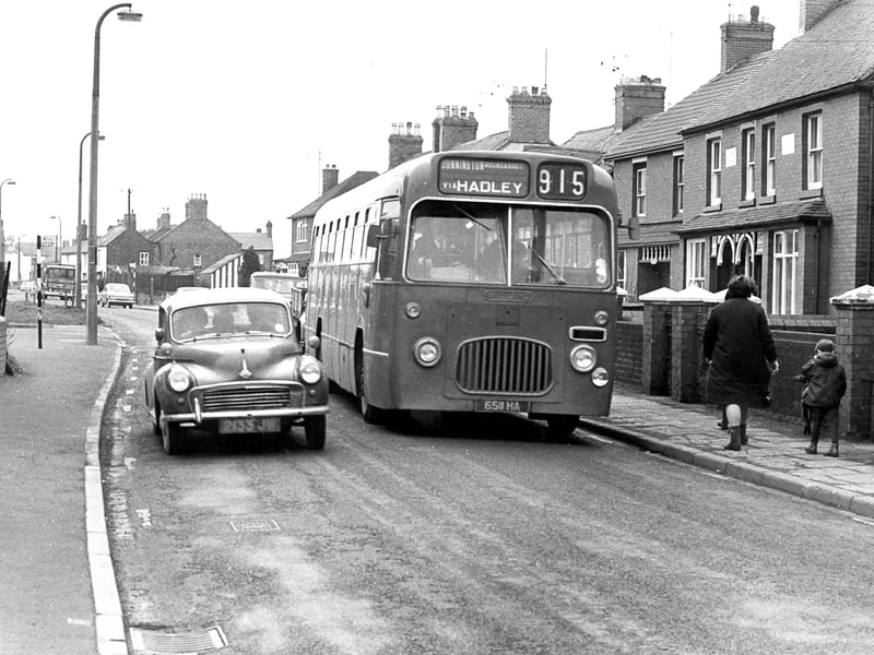 Telford's Trench Road traffic in March 1971 shows a Midland Red bus and Morris Minor car passing through a typical street scene of the time.