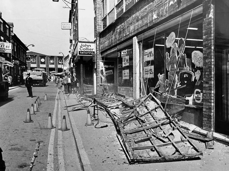 A familiar Oswestry street scene - but with a dramatic story behind it. In May 1975, a Fine Fare supermarket sign became part of a major incident when falling wood and masonry narrowly missed a shopper. Can you spot the old John Collier shop and other high street details?