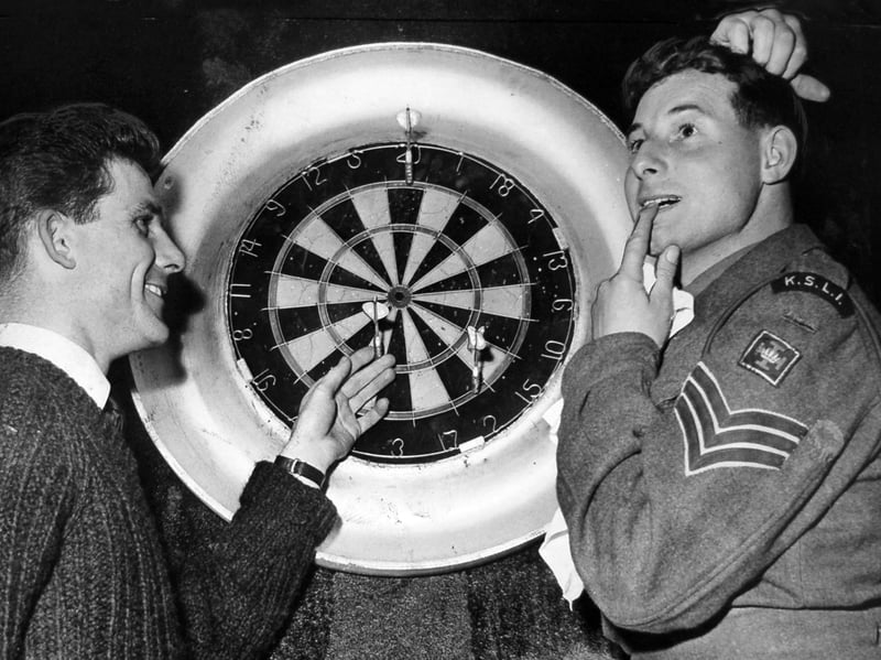 Points are tallied in good humour as Sergeant Dan Powell (left), captain of the North Shropshire Squadron, Shropshire Yeomanry darts team, shows off his winning checkout to a jovial Sergeant Ted Grey at Shrewsbury Drill Hall in April 1963. Heading up 'B' Company KSLI from Oswestry, a theatrical Sergeant Grey looks on in comical dismay as Powell points out his final darts. The playful moment was captured during the annual Shropshire Territorial and Auxiliary Association darts and dominoes competitions, bringing together service personnel from across the county for an evening of friendly competition. Did you take part in the Territorial Army sports nights at Shrewsbury Drill Hall, or do you remember Sergeant Dan Powell and Sergeant Ted Grey from the 1960s?