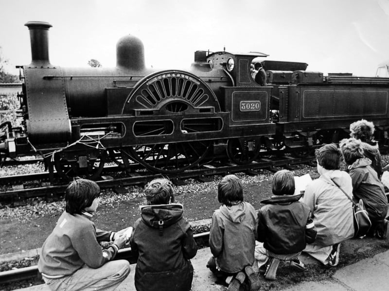 A line of young train spotters kneel along the platform edge on August 16, 1979, marvelling at the historic former London and North Western Railway locomotive Cornwall as the Victorian single-driver engine pauses in Shrewsbury while en route to Bridgnorth workshops for an overhaul. Were you among the young rail enthusiasts watching the historic engine steam through Shrewsbury that summer? What are your favourite memories of train spotting beneath the station canopy during the 1970s?