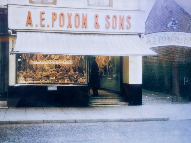 The welcoming storefront of A. E. Poxon & Sons butchers on Brownhills High Street captured in vibrant colour around 1960 by photographer Jon Lucas. With fresh cuts of meat neatly displayed behind the glass window, a striped sun awning extended, and painted signage pointing down the side passage to their 'Model Abattoir & Pork Factory', the family business was a cornerstone of local trade. Serving generation after generation of local shoppers, the shop stood out as a proud example of the independent high street butchers that defined everyday life in the borough. Did you or your family buy your Sunday roast or famous local pork sausages from Poxon's?