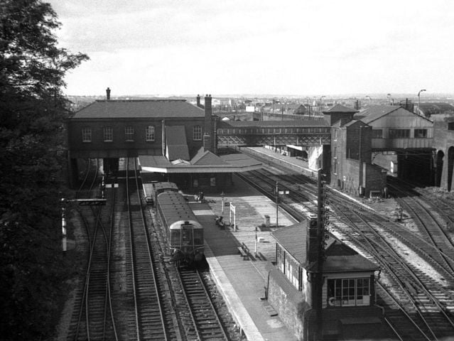 A high-angle view captures the sweeping, quiet layout of Dudley railway station in 1962, showing a lonely diesel train resting alongside the platforms surrounded by empty tracks, signal boxes, and footbridges. Once a vital transport link connecting passengers right across the West Midlands, the historic station saw its passenger services closed just two years later in 1964 as part of the Beeching cuts. Decades on, passionate local campaigners continue to champion calls to bring passenger trains back to Dudley, keeping memories of this major railway junction alive. Do you remember traveling through Dudley station before it closed, or would you like to see passenger rail return to the town?