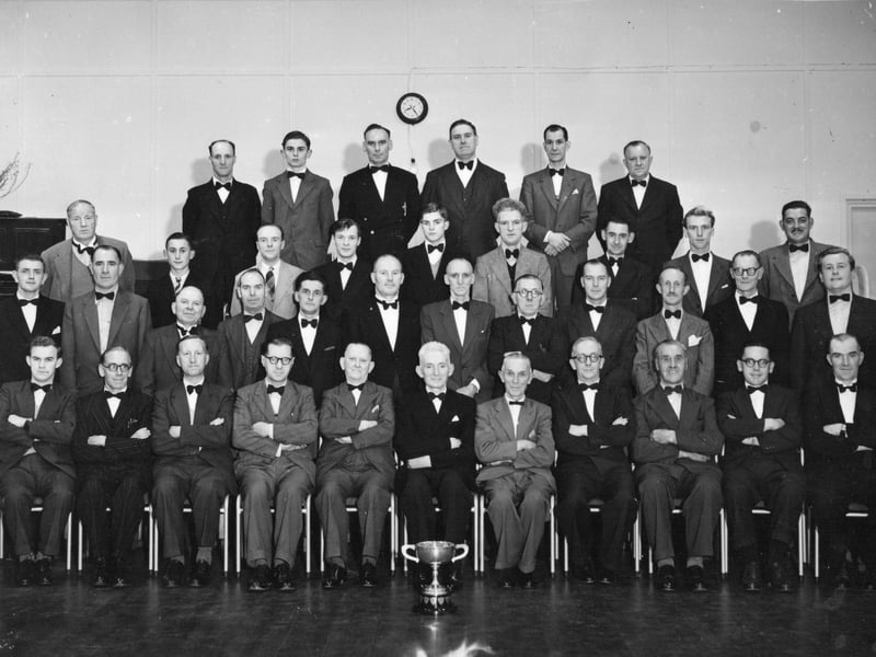Dressed in smart suits and bow ties, members of the Donnington Wood Male Voice Choir pose for a formal group portrait alongside their silverware trophy circa October 1961. Sent in by former local Harry Bouckley, whose father William (Bill) Bouckley sang tenor with the ensemble, the image captures a dedicated group of singers who regularly rehearsed at the nearby Wrockwardine Wood Girls School. After working through their musical repertoire, choir members would famously pop across the road to quench their thirst at the Fountain pub. The photograph is a wonderful slice of local musical tradition. Do you remember hearing the Donnington Wood Male Voice Choir perform in the early 1960s, or can you spot any familiar faces among the singers?