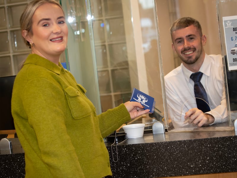 Leanne Totton handing over her Credit Union book to Feargal Reid during her visit to Saturday's International Credit Union Day celebrations.
