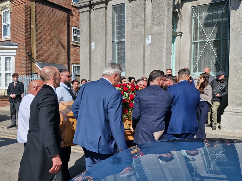 Hubert's family, including grandsons and his son Hubert, carry the coffin into the church