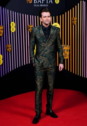 Instead, he walked the red carpet in a green and gold suit which appeared to feature an intricate horoscope-inspired pattern.