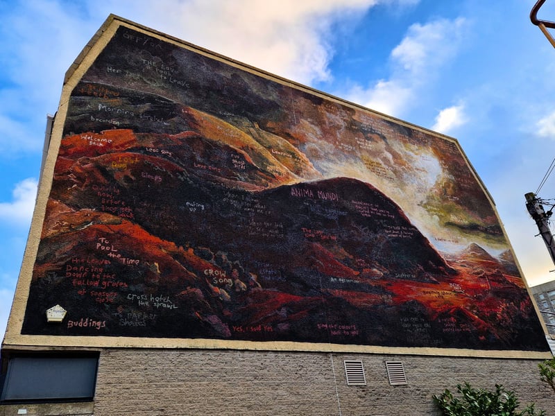 London artist HICKS is responsible for two works for Nuart 2026, such as the one which now lives on the side of MERKUR Casino on Summer Street. A beautiful landscape in his typical style, there are various phrases scattered across the work. 
