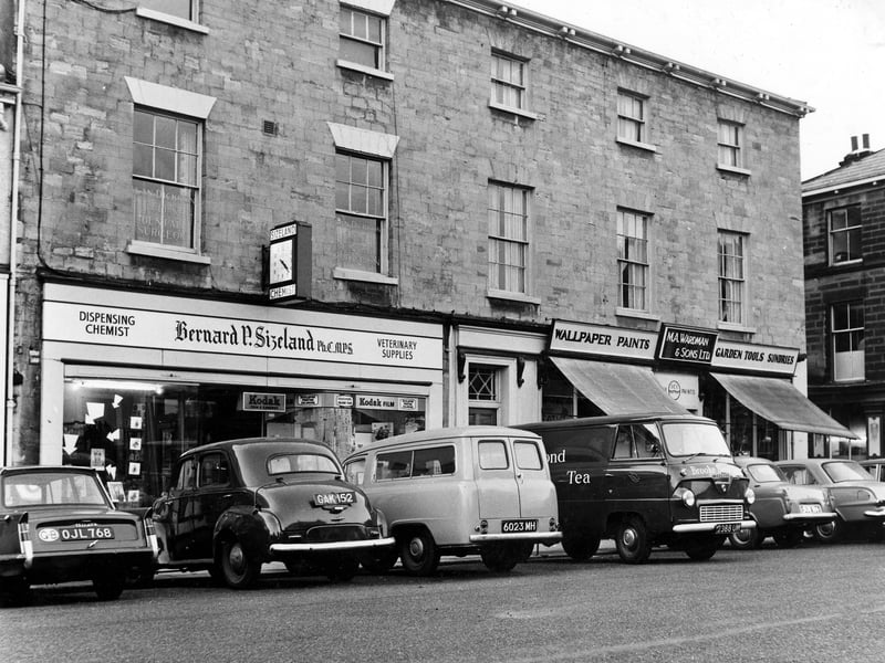 Market Place in November 1962. On the left is Bernard P. Sizeland, Dispensing Chemist and Veterinary Supplies. It occupies what was once the old post office at number 19 Market Place, and is still in business today. On the right is number 21, M.A. Wardman & Sons Ltd.' Wallpaper, Paints, Garden Tools and Sundries.