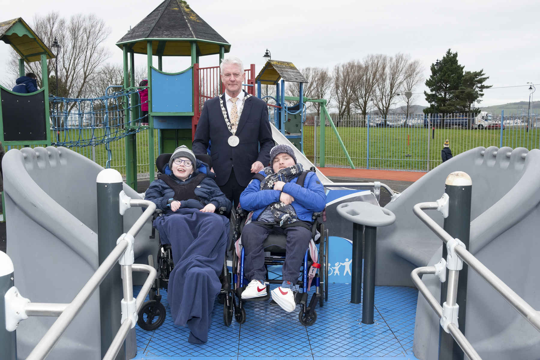 Waterford City and County Council recently completed the installation of three wheelchair accessible swings at the People’s Park in Waterford city, Walton Park in Dungarvan and the Inclusion Park in Tramore.  Mayor of Waterford City and County Cllr. John O’Leary welcomed the addition of the accessibility swings to the three sites. “These pieces of equipment are more than just swings, they are integral in promoting inclusivity, and providing children with disabilities or mobility issues equal access to playground facilities.”  “Judging by the smiles on the faces of the students and staff of St. John’s Special School, there’s no doubt that the accessibility swing in Walton Park is already a big hit with the children.” Read more below Mayor of Waterford City & County Councillor John O'Leary pictured with Philip Daly and Ryan Hurley, both from Tallow at the new accessibility swing in Walton Park, Dungarvan.  Images: David Clynch The swings, which have a capacity for two wheelchairs and up to eight people are accessible 24/7, without key access or the need for a harness.  Located centrally in each park, the swings are part of the Council’s initiative to encourage inclusive play and social interaction. Jennie Moore, Teacher at St. John’s Special School in Dungarvan added, “The accessibility swing is a fantastic addition to Walton Park. While there are so many great playground facilities in the locality, the addition of this newest piece of equipment is to be welcomed.  “Already our students are reaping the rewards of being able to play together and the fact that we can access the swing whenever we are in the park is a bonus. We are currently planning school trips with our students and the accessibility swings in the city and Tramore are certainly on our to-visit list!” Sean Gormley, Executive Engineer with Waterford City and County Council explains the idea behind the swings. “Within the last few years, the Council has been committed to promoting inclusive social