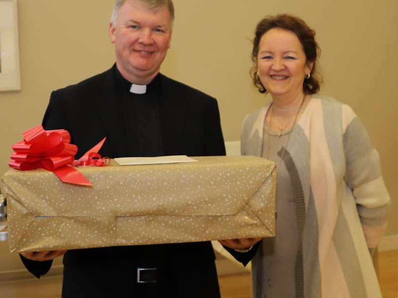 Mella Britton, member of the Parish and Fundraising Committee makes a presentation to Fr Niall Coll.