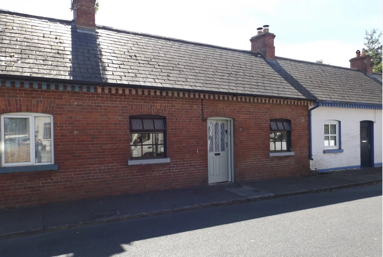 With little or now houses to rent, maybe its time to buy. Some are affordable such as this the period terraced cottage in Ballinakill. The two bed, one bathroom 63 m² red-brick house is on the market through Clemont Heron at an asking price of €119,000. Tap NEXT or the > to see more pictures or see below photo to read more about the property in the village not far from the Kilkenny border. "We are delighted to offer this exceptional residence to the market. This is a well presented two bedroom mid terrace cottage/bungalow with ample outdoor space," say the estate agents. They say the accommodation consists of living room, galley kitchen, two bedrooms and main family bathroom. Accommodation: Living room: 4.402m x 4.02m With curtains, poles and blinds and wooden flooring. There is a solid fuel stove which also heats the radiators throughout the house. Galley kitchen: 2.125m x 1.85m The floor and splash area are tiled and it comes with a gas cooker. Bathroom: 1.56m x 1.79m With w.c., wash hand basin and corner shower with a t90i electric shower. Bedroom 1: 3.075m x 2.14m With wooden flooring, curtains and poles. The window is north facing. Bedroom 2: 3.1m x 2.15m With wooden flooring, curtains and poles. The window is south facing. OUTSIDE: The rear walled in garden is 8m x 11m, it is south facing and retains some old original features including the old Pig house and outdoor WC. On exiting the garden to the rear, one can go left to visit the huge paddock also included with this house. To the right will bring one to the street. Key accompanied viewings by appointment only. Property Features Quiet village location
0.25 acre paddock/allotment to the rear
South facing garden
Terrace with ample rear access
Solid fuel central heating