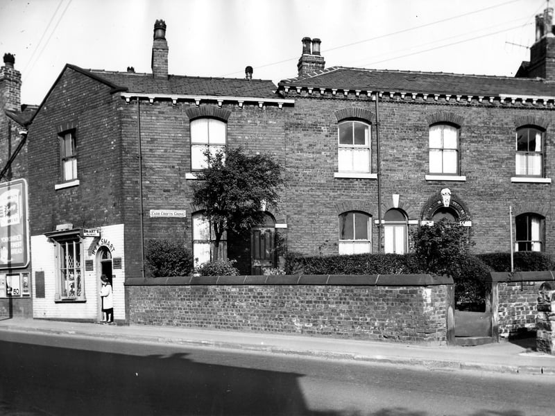 On the left of the image is number 232 Tong Road, the H & N Smart florist, offering wedding bouquets and cremation sprays and wreaths. On the far left can be seen a large advertising hoarding promoting bread. On the right are numbers 1 and 1a Carr Crofts Grove. Pictured in September 1966.