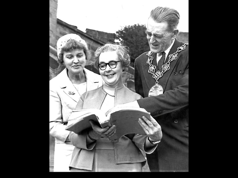 October 1961: The photograph shows Shropshire author Edith Pargeter, who lived in Madeley at the time and also wrote under the name Ellis Peters. Despite damage to the original caption, it records members of a Library Association branch being shown around Shrewsbury and later entertained at Shrewsbury Castle with a buffet tea hosted by the Mayor, Councillor R.J.H. Edwards. In the image, Miss Pargeter is seen (centre) displaying the manuscript of her historical novel The Heaven Tree, set in the 13th century with Shrewsbury Castle featuring prominently, alongside Birmingham branch chairman Mrs SMT Stone.