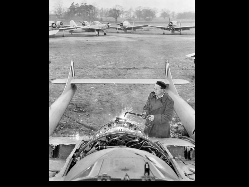 An aircraft graveyard at RAF Shawbury in February 1961, where a de Havilland Vampire jet is seen being broken up for scrap, with Percival Provost aircraft standing in the background.
