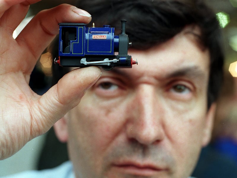 This is Brian Caton who hand built this, 009 N Gauge 4mm, Saddle Tank engine believed to be the smallest live steam engine in the world. He is pictured at the 1999 National Model Engineering & Modelling Exhibition.