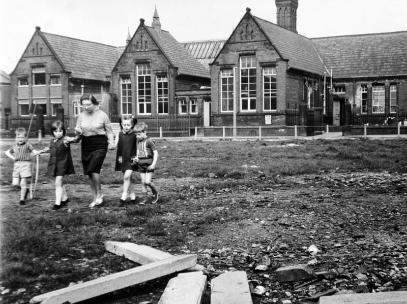 June Brelsford, headteacher of Whingate Road Primary School, Leeds, walks across the playground with pupils, Simon Allan, Sally Nelson, Carolyn Dawson and Philip Snelson, all aged five, in May 1970