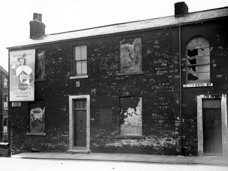 Numbers 28 and 30 Arthur Street, at the junction with Stoney Rock Lane. Number 30 has four windows filled in, the lower left one bearing a torn Police Notice offering a reward of ten shillings. Pictured in May 1956.