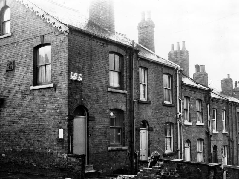The rear yards and entrances of a row of through terraced houses numbers 4 to 12 Edwin Road. The wall of number 4 in the foreground has been knocked down. Visible on the left is King's Road. Pictured in December 1972.