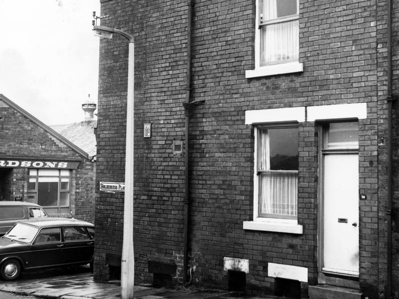 The front of a through terraced house at the bottom end of Holderness Place. On the far left cars are parked in front of a business at number 37 Queen's Road. Pictured in December 1972.