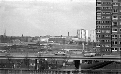 A raised section of Lovell Park Road runs across the foreground of this view. On the right edge, Lovell Park Towers flats are visible. In the background St James's Hospital can be seen to the left with flats on the Shakespeare estate to the right. View looks across Sheepscar, then Burmantofts. 