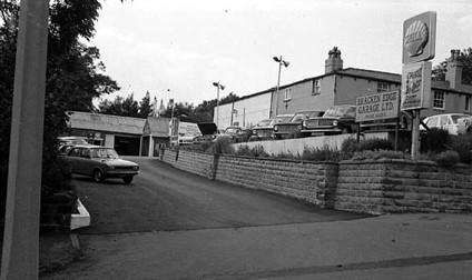 This view looks onto the forecourt of Bracken Edge Garage Ltd, on Sycamore Avenue. The garage offered motor repairs and alos sold petrol. A Shell sign is visible towards the right.