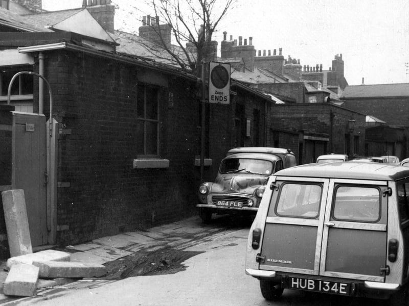 Looking west along the south-west side of Back Queen Square in November 1968. Cars and vans are parked in the foreground (including a Mini-Minor). Stone slabs are piled in the corner, where building work is taking place.