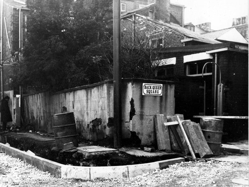Back Queen Square, just off Woodhouse Lane in November 1968. The path is under construction, as is the road. Paving slabs are leant up against the wall. Two oil drums and some wooden planks are visible.