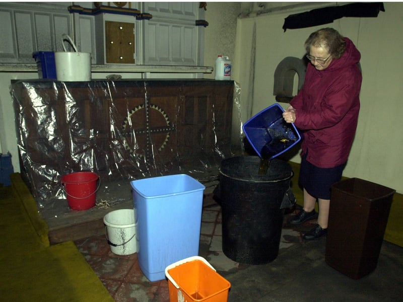 St. Hilda's Church verger Margaret Croll mops up rain in the church after thieves stole the roof tiles. Pictured in November 2000.