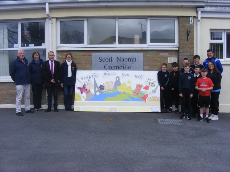 St Colmcille's National School - ‘Oh the places you will go’ Dr. Seuss Our mural is not only inspired by Dr. Seuss but by our own school and the journey that each child goes on from the moment they enter in 1st class until they leave us in 6th class. The base of our mural is the top of our own school building where this journey begins. Through visiting and connecting with our locality our students learn so much more about the history of our beautiful town, church and park, flora and fauna, minibeasts, map reading etc. Through this journey they achieve a great sense of belonging and pride. We have included each element of our crest into our mural which represents our many talents such as reading, sport, music and art. We are very lucky to be part of a town which develops these talents further. Through reading and discussion our students go on an imaginative journey to further corners of the world, visiting the round towers of Ireland, the pyramids of Egypt and the Eiffel tower of France. Our mural reminds us all that we have so much to be grateful for, not just in our beautiful locality but in the world all around us. It also reminds us that no matter where we travel or visit on our journeys there is no place like home. Returning to normality in our community, the sun and sunflower in our mural represents brightness and positivity for the future of all who spend time in our town and surroundings. We are so proud of all of our students who worked on this project. We would also like to express our thanks to our past pupil Roy Doran for sharing his amazing talents since he began his journey with us. We appreciate all his guidance, patience and hard work on this project. He is truly an inspiration for all our students. We would like to thank Saoirse Faherty a TY student from Our Lady’s who also was willing to share her talents with us to complete this project. We are so grateful for the Lions club for giving us this opportunity to share our talents.
