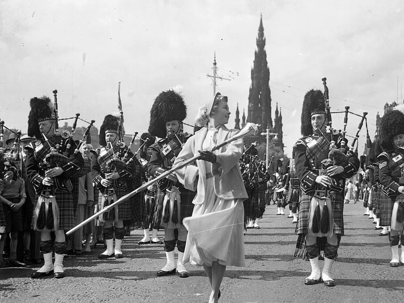 American actress Vera-Ellen leads a pipe band in Princes Street whilst filming the 1956 movie Let's Be Happy.
