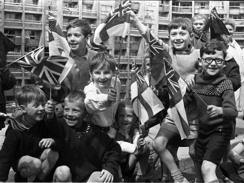 Children wave flags at the Hyde Park flats, in Sheffield, for the Queen Mother's visit on June 23, 1966