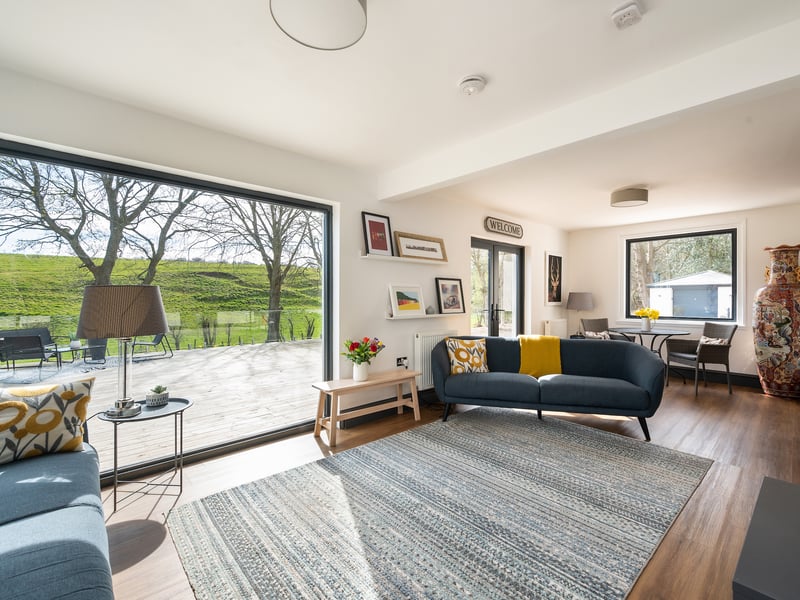 The south facing contemporary sitting room, with a wood burning stove, is flooded with natural light from picture windows and has french doors to a large terrace.