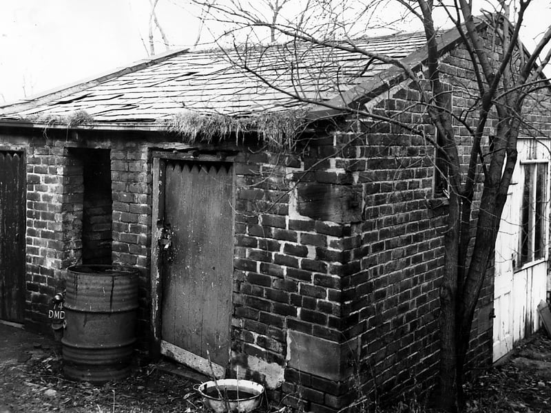 An unidentified brick building on Tower Lane pictured in November 1963. The doors on the left may have been outside toilets. In the central opening is being used to store a motorbike. To the right is a white painted door and window. This part of the structure may have been a shed or a workshop.