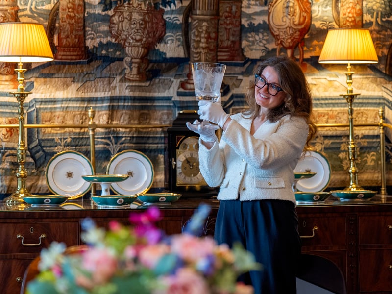 A member of staff from the Royal Trust Collection takes a closer look at an engraved glass goblet, the Reddendo presented to late Queen Elizabeth II in 1976 by the Royal Archers, which is on display in the Royal Breakfast Room at the Palace of Holyroodhouse in Edinburgh, the official residence of the monarch in Scotland.