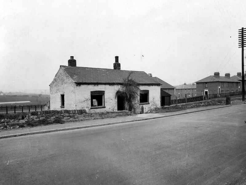 An old derelict cottage on Dewsbury Road in October 1933, located close to the junction with Millshaw Road, visible in the background. The block of houses on the right are numbered 548-554 Dewsbury Road while behind them are numbers 67-73 Millshaw Road. The old cottage has since been demolished.