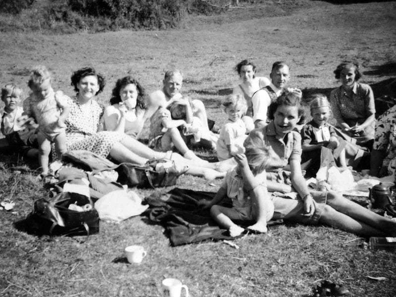 An outing to Coalport in 1949, shared by Jean Hassall. The group travelled by train from Stirchley with a picnic, kettle and teapot in tow, enjoying a day by the river with friends and neighbours from Hinkshay, Dawley and surrounding areas. Pictured are Jean Oakley (fourth from left, drinking from a cup), her sister-in-law Josie Oakley, young Keith Oakley (second from left), Jenny Harris (front centre right) and her son Adrian Harris, along with other unnamed companions.