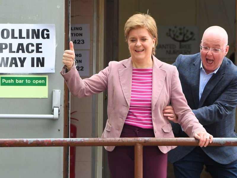 Scotland's First Minister and Scottish National Party leader Nicola Sturgeon reacts as she is surprised by her husband and current chief executive officer of the Scottish National Party Peter Murrell, after casting their vote in local elections, at a polling station, in Glasgow, on May 5, 2022. 