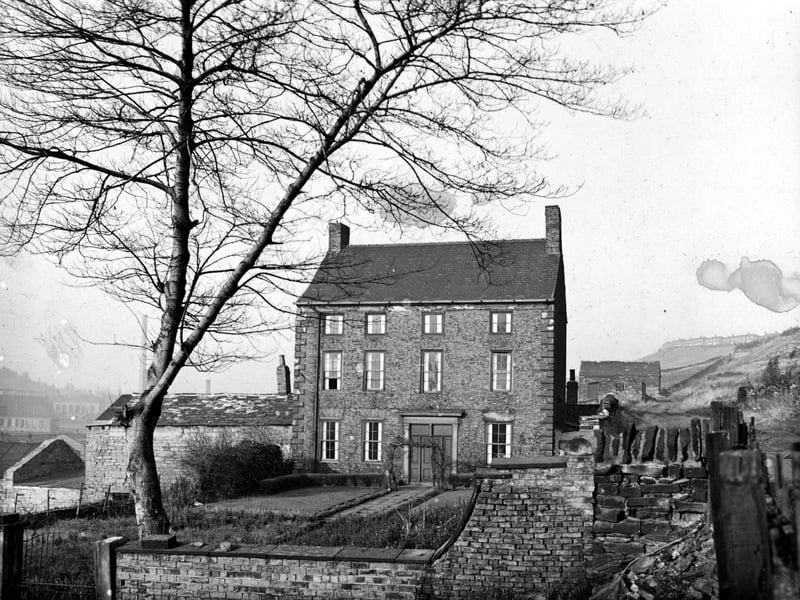Front view of Scott Hall, a large brick built building with a garden surrounded by a wall. A steep, grassy hillside is to the left. This is not the original Scott Hall which was sited further north in Potternewton just south of Potternewton Lane. Pictured in November 1948.