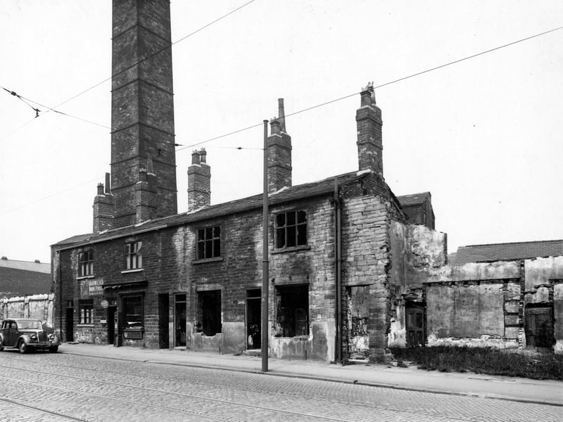 The north-east side of Meanwood Road, showing nos. 294 to 300. On the left a car is parked on the road, which is laid with tramlines. A large industrial chimney shows behind the houses. Pictured in June 1949.