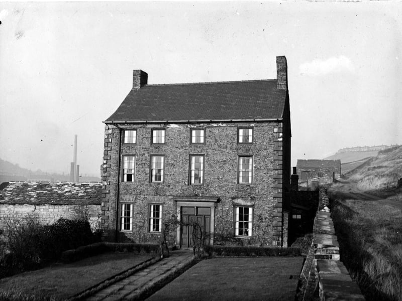 The front of Scott Hall, a large mid eighteenth century house, built in brown hand-made bricks, with an outbuilding on the left. This is a rare example of the type of plain house built by Leeds merchants during that period and it is now Grade II listed. Pictured in November 1948.