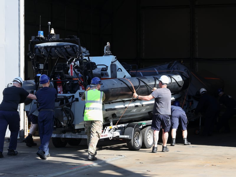 Members of ships company putting a sea boat in the hanger of RFA Lyme Bay.