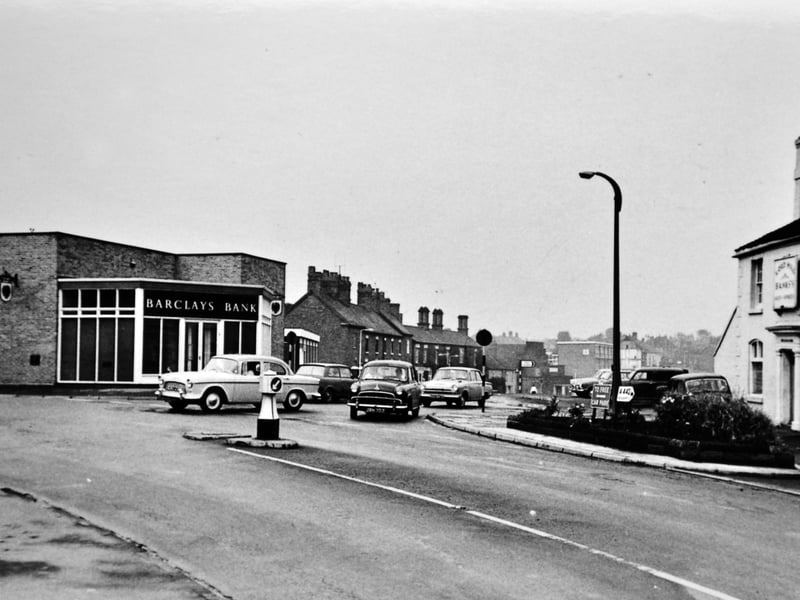A street scene showing the junction of King Street and High Street, likely taken in the late 1960s. King Street runs to the right, with High Street leading off to the left. The Lord Hill pub stands on the right, with Barclays Bank just left of centre. In the distance are modern flats on King Street, built in 1964 beyond the Royal cinema, helping to date the image. The photograph forms part of a series sent to postcard collector Ray Farlow, and is believed to have originated from Shropshire Postcard Club material